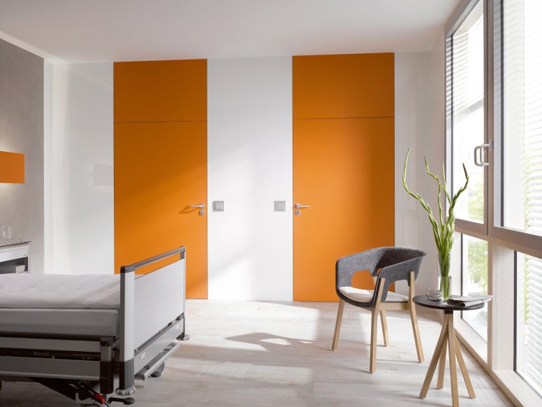 Chambre d'hôpital blanche avec deux portes orange équipées d'une poignée de porte en polyamide de couleur grise